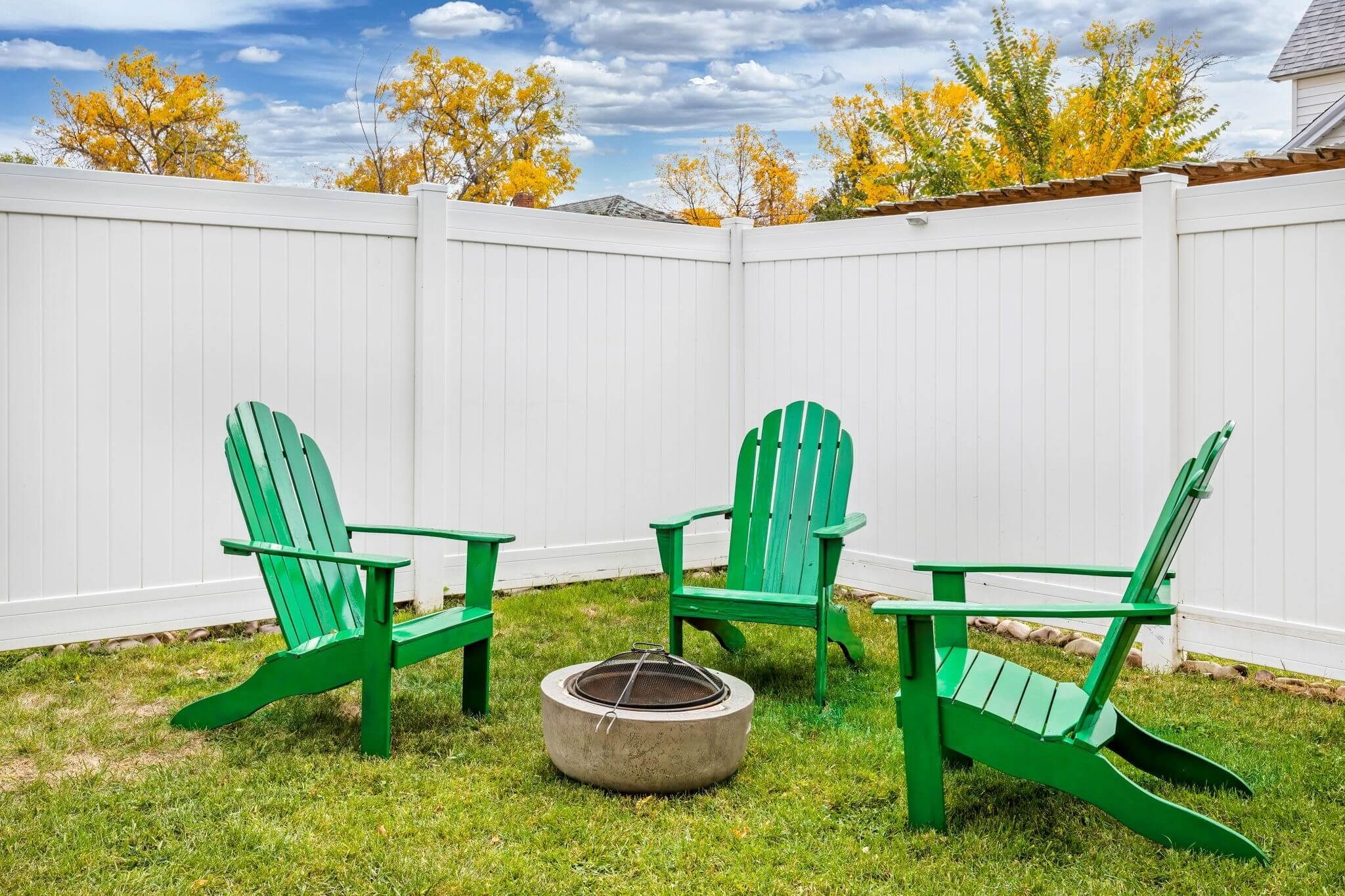 Private backyard with green Adirondack chairs and fire pit, offering the perfect spot for cozy outdoor evenings at Wrecked & Refined vacation rental in Great Falls, Montana.